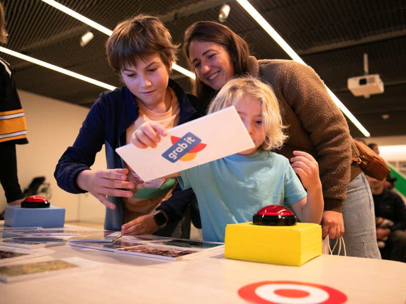 Children and a parent playing the Grab It card game at a museum table